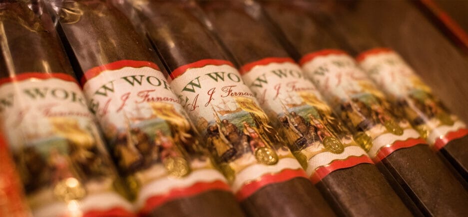 Close-up of a row of cigars with ornate labels featuring historical artwork in a climate chamber.
