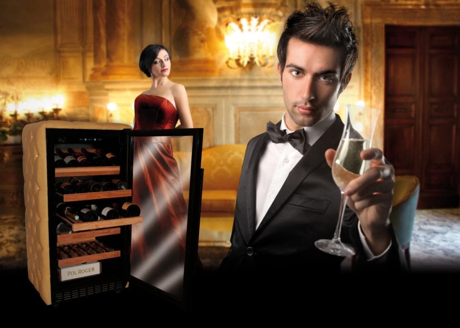 A man in a tuxedo holds a glass of champagne and stares into the camera, while a woman in a red dress and a champagne storage cabinet filled with bottles stand in an opulent room.