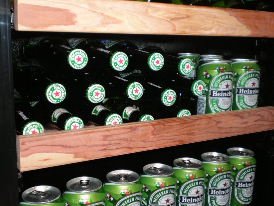 Wooden shelf filled with rows of beer cooler cans and bottles.