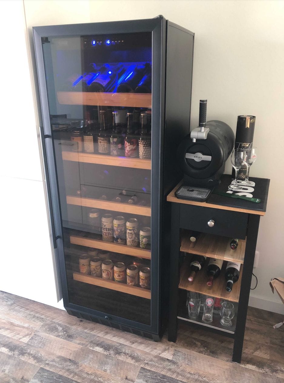 Een bierbewaarkast (275 liter) in een woonkamer met daarnaast een biertap met bierglazen voor een ultieme beleving.