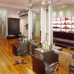 Intérieur de salon de coiffure moderne avec chaises de styliste, miroirs et étagères remplies d'armoires climatiques à bière (190 litres, hauteur 124 cm, zones multiples).