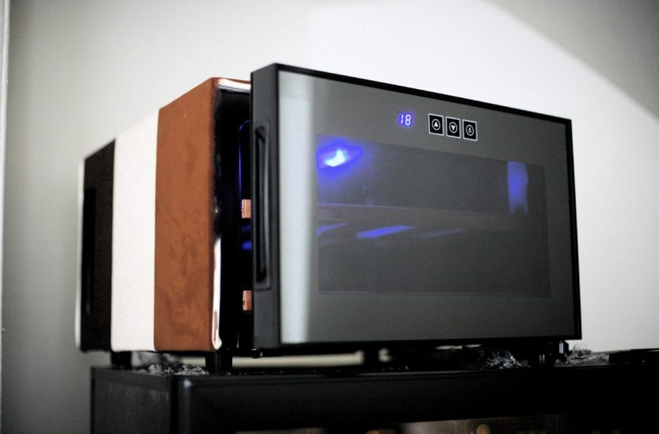 A modern Chocolate climate cabinet (25 liters) with a digital display that shows the time, sitting on a countertop with a wooden panel on one side.