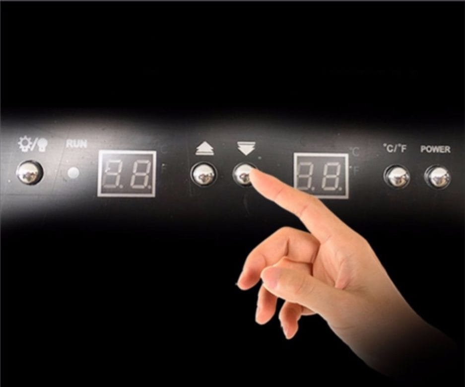 Een vingerdruk op de aan/uit-knop van een Wijnklimaatkast (200 flessen*, meerdere zones, 180cm hoogte) met verlichte temperatuurdisplays.