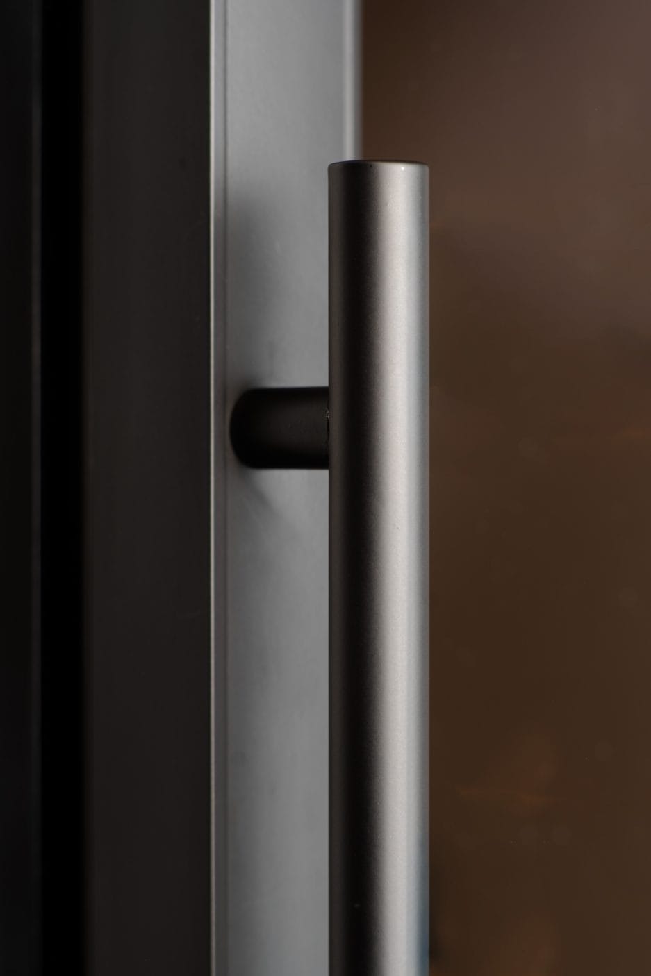Nahaufnahme eines Bierklimaschranks (190 Liter, Höhe 124 cm, Mehrzonen) an einer dunklen Glastür, die das schlanke, zylindrische Design und die matte Oberfläche hervorhebt.