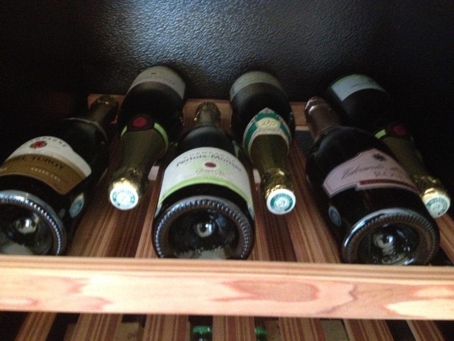 Ein Champagner-Lagerschrank mit mehreren Flaschen Wein, von unten gesehen, mit Etiketten und Böden der Flaschen.