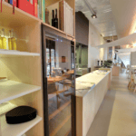 Intérieur d'un restaurant moderne avec étagères en bois remplies de cave à vin (120 bouteilles, zones multiples, hauteur 164 cm) et tables dressées pour les repas.