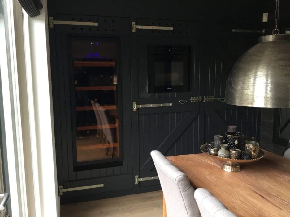 Kamer, voorzien van een Wijnbewaartkast (max 120 flessen, 164 cm hoogte) met glazen deuren, een houten tafel, metaalkleurige hanglamp en een grijs gestoffeerde stoel.