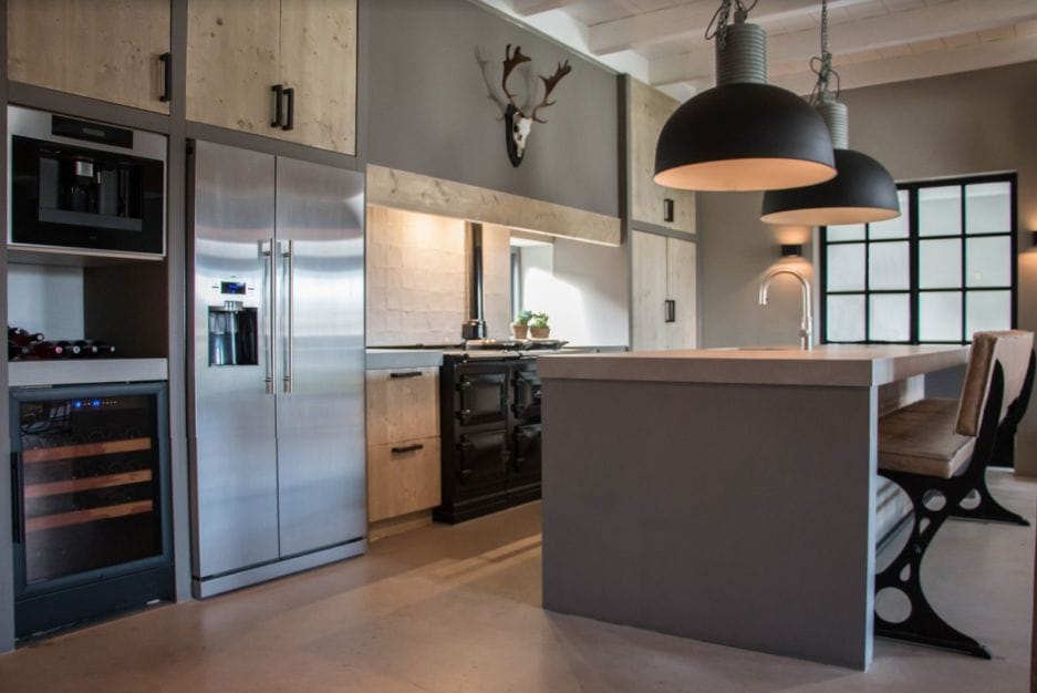 Modern kitchen interior with a Wine cooler (40 bottles, multi-zone, 84cm height), a central island, hanging lamps and a deer head mounted above cabinets.