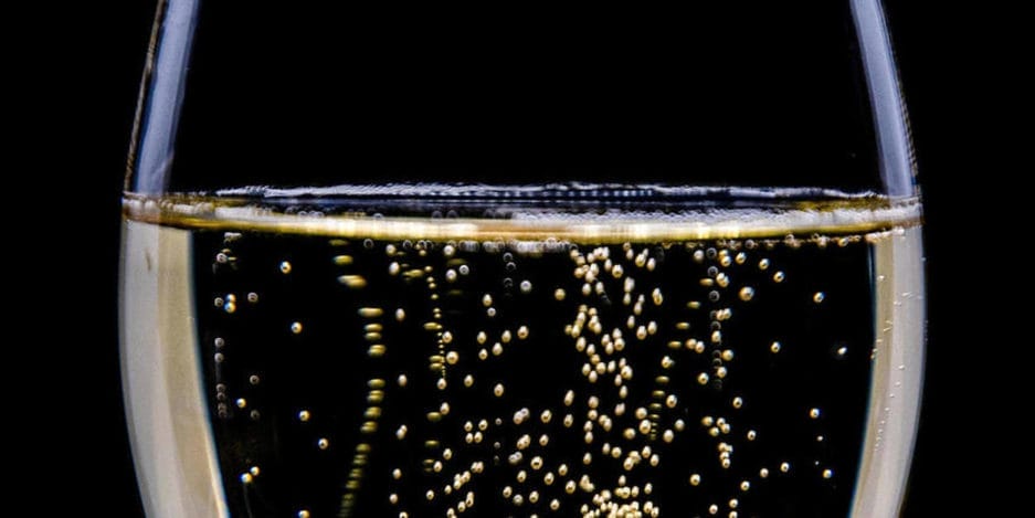 Eine Nahaufnahme eines Champagner-Lagerschranks (25 Liter) mit an die Oberfläche aufsteigenden Blasen vor schwarzem Hintergrund.