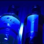Drie Wijnbewaarkast (200 flessen, één zone, 180cm hoogte verlicht door blauw licht, opgesteld op een plank.