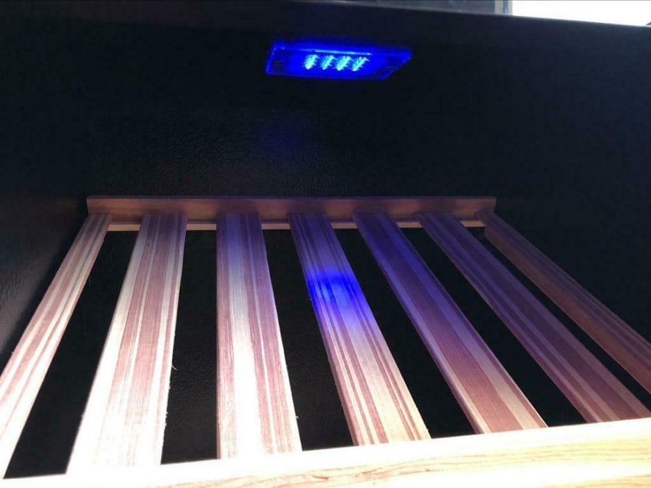 Innenansicht eines Lagerregals mit violetter LED-Beleuchtung, die die Lampen und Schutzgitter zeigt.