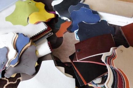 Plusieurs échantillons de cuir de différentes couleurs et textures répartis sur une table.