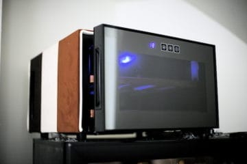 Een moderne magnetron met de tijd '18' en gedeeltelijk bedekt met een wit-bruine hoes, geplaatst op een zwart oppervlak in een slecht verlichte kamer.