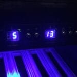 Beleuchtetes Bedienfeld mit digitalen Temperatureinstellungen, hervorgehoben durch blaue Hintergrundbeleuchtung, über einer Reihe von Schaltern und Drehreglern.