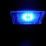 Une lumière LED bleue qui brille dans l'obscurité, enfermée dans un boîtier rectangulaire translucide avec une surface texturée.