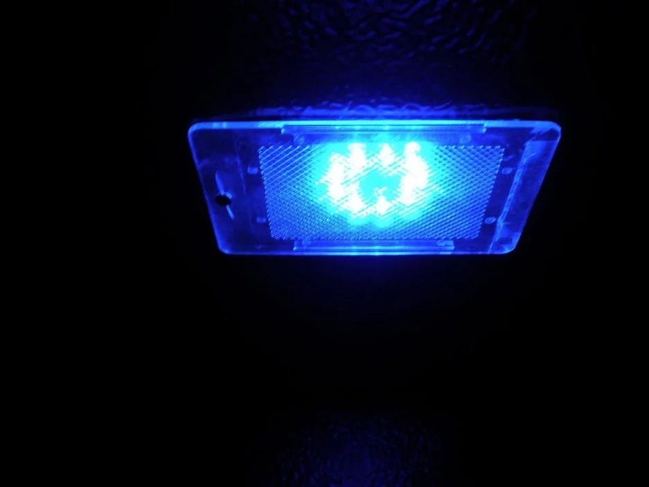 Een blauw led-licht dat gloeit in de duisternis, ingesloten in een doorzichtige rechthoekige behuizing met een gestructureerd oppervlak.