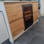 Eine moderne Küche mit Holzschränken mit eingebautem Backofen und Kühlschrank mit Fliesenboden.