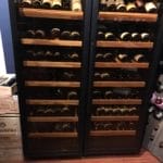 Une cave à vin remplie de rangées de différentes bouteilles de vin, exposées dans une armoire en bois avec portes vitrées.