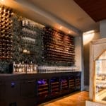 Een moderne wijnkelder met uitgebreide flessenrekken aan de muur, een glazen kaasvitrine en een stijlvol, ruim interieur.