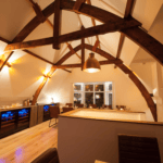 Interieur van een gezellige keuken met zichtbare houten balken, warme verlichting, een bar en moderne apparatuur.