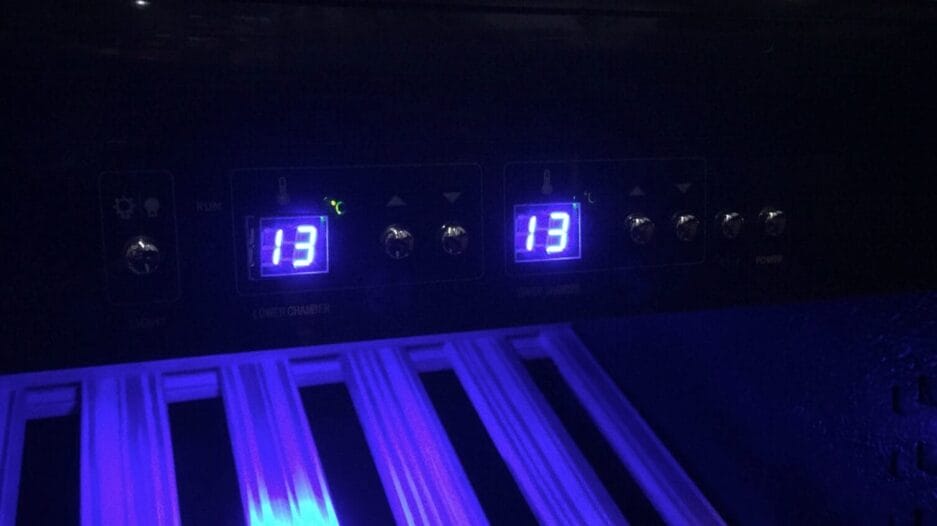 Bedieningspaneel van de kast met verlichte cijfers in blauw licht, waarbij het getal 13 op twee schermen (1 = ingestelde temperatuur en 2 = daadwerkelije temperatuur) wordt weergegeven.