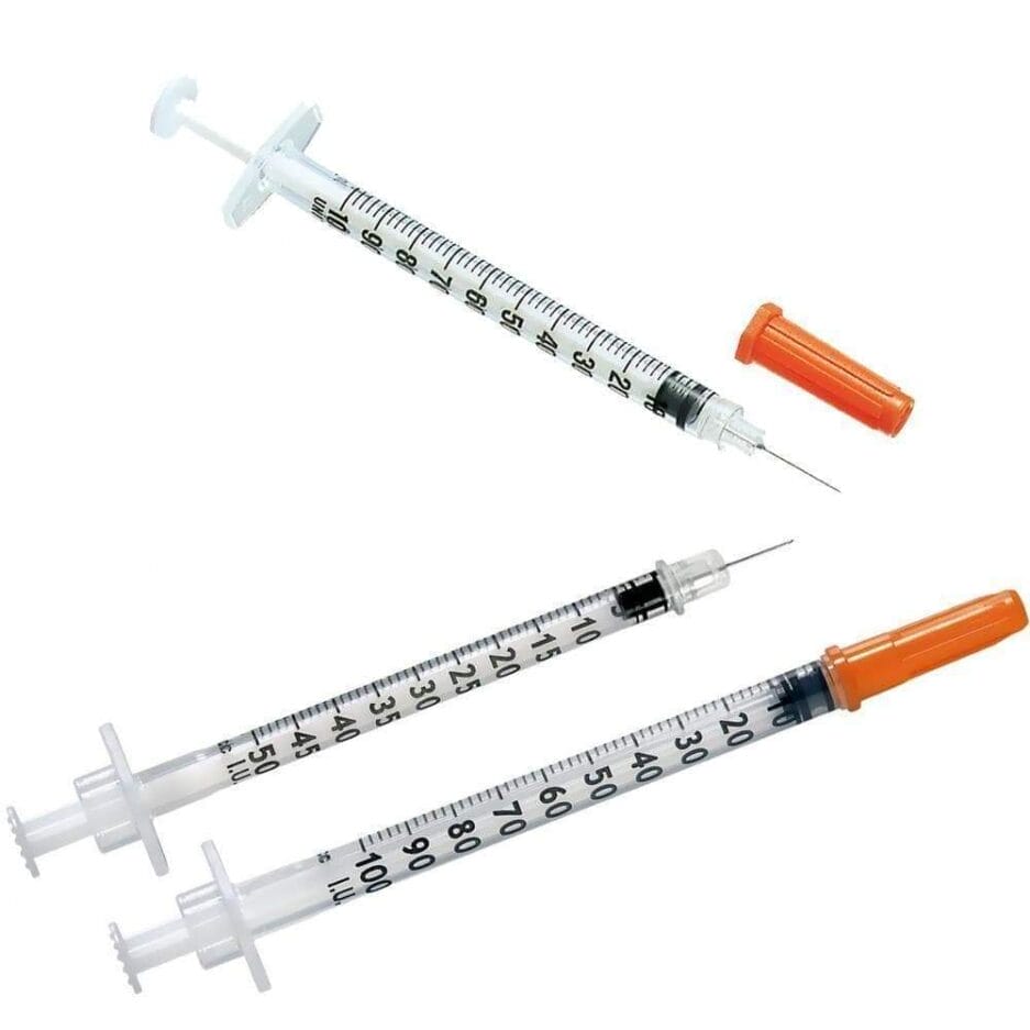 Drie medische spuiten met naalden en oranje doppen, diagonaal weergegeven op een witte achtergrond.
