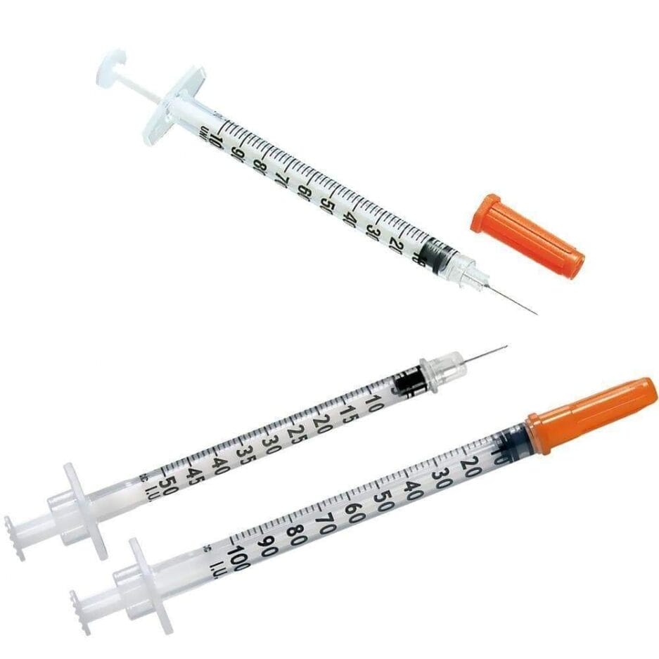 Trois seringues médicales avec aiguilles et capuchons orange, présentées en diagonale sur fond blanc.