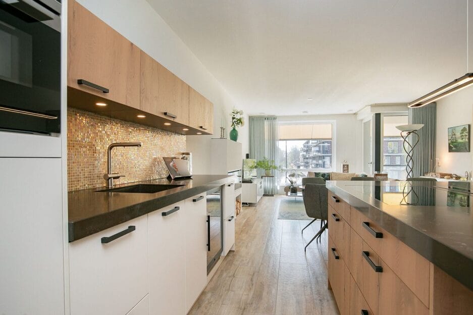Modern keukeninterieur met witte kasten, houten accenten en een wijn bewaarkast.
