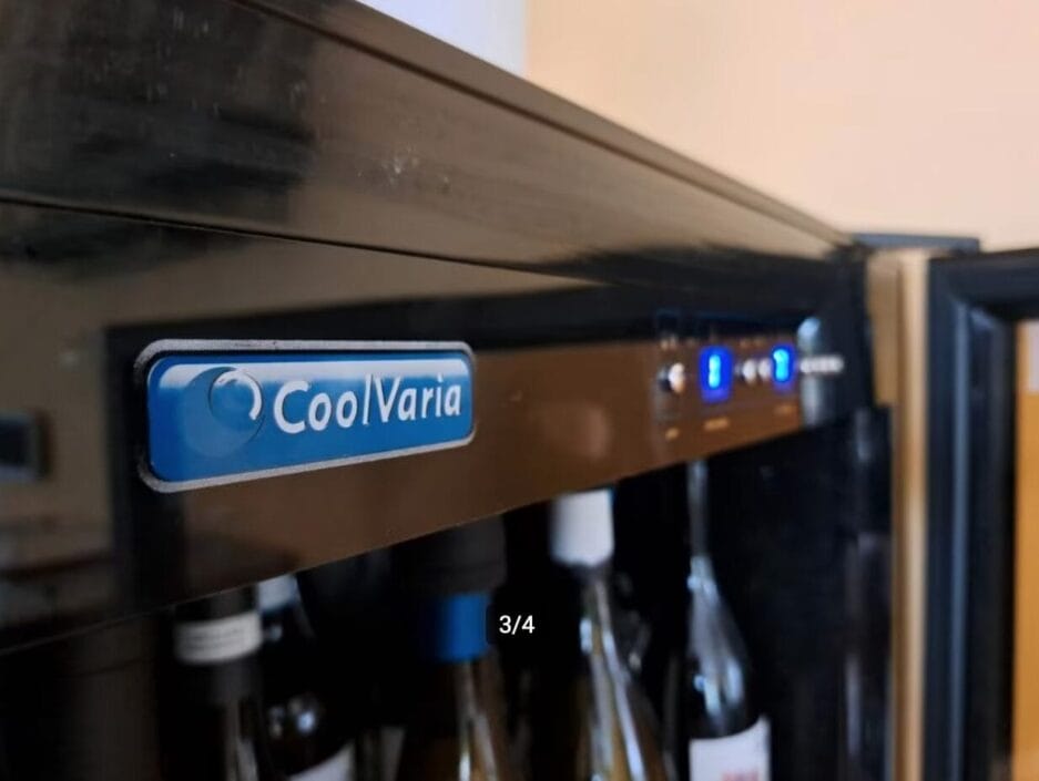 Wijnbewaarkast met het opschrift "coolVaria" met digitaal temperatuurdisplay, gedeeltelijk met flessen erin.