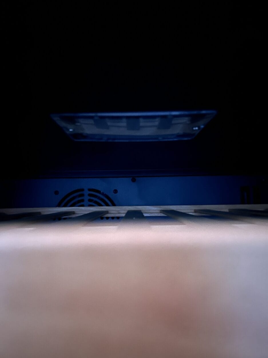 Close-up van de binnenkant van een klimaatkast, met lamp en een ventilator aan de achterkant.