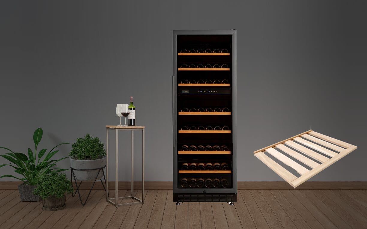 Hoher Weinkühlschrank, gefüllt mit Flaschen, auf einem Holzboden stehend. Daneben steht ein kleiner Tisch mit zwei Weingläsern und einer Flasche. Auf der linken Seite stehen zwei Topfpflanzen. Eine leere Weinregalschublade schwebt.