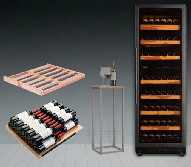 On the right is a wine fridge full of bottles. On the left are two wooden wine racks. In the middle is a small table with two wine glasses and a bottle.